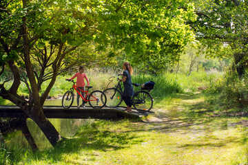cute little girl and her mom crossing a small wooden bridge by bike