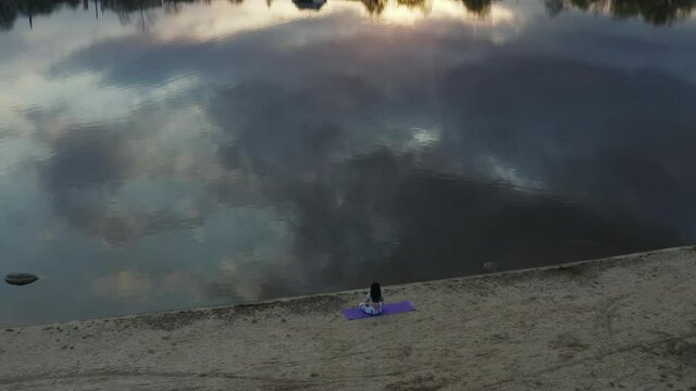 Woman yogina practicing yoga, respiration of Pranayama in the nature near the lake at sunset