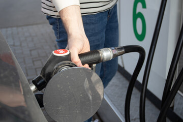 A man refueling the car on gas station. Petrol Station. Gas pump close up. An automobile is getting refueled by a petrol pistol