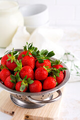 Fresh strawberries ripe delicious in colander bowl on white stone background with copy space. Selective focus.