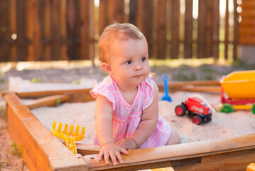 Adorable baby play with sand in sandbox on playground