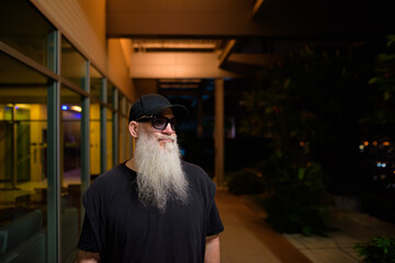 Obraz premium Portrait of mature man with gray beard outdoors at night thinking
