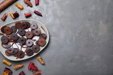 Delicious fruit leather rolls on grey table, flat lay. Space for text