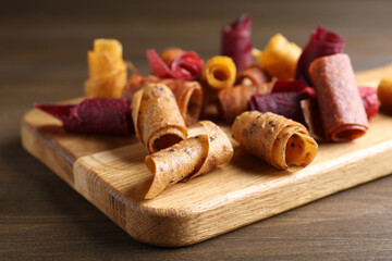 Delicious fruit leather rolls on wooden table, closeup
