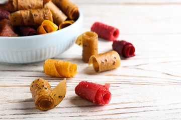 Delicious fruit leather rolls on white wooden table, closeup