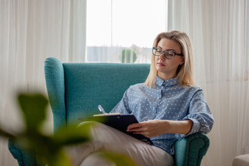 Woman psychologist or psychotherapist with eyeglasses sitting in armchair