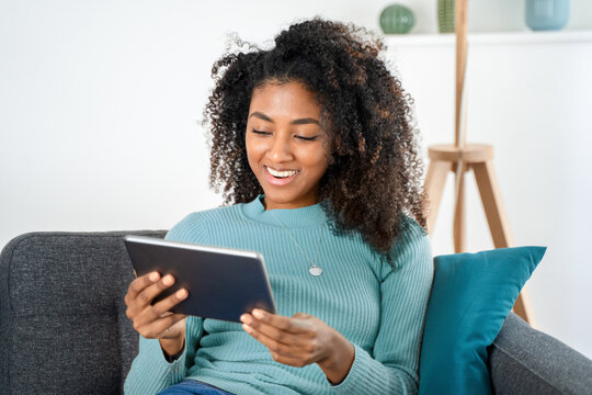 Happy black young woman using digital tablet at home