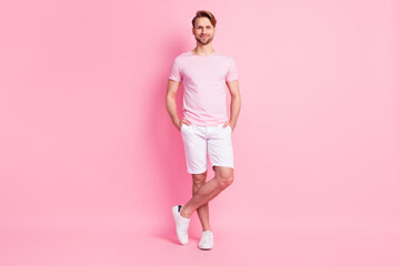 Photo of charming sweet young guy wear casual clothes smiling arms shorts pockets isolated pink color background