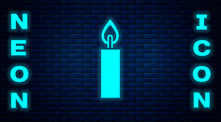 Glowing neon Burning candle icon isolated on brick wall background. Cylindrical candle stick with burning flame. Vector