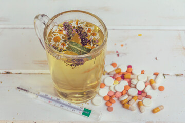 Cup of Healthy Herbal Tea with Dried Chamomile Flowers , Thyme, Thermometer and Pills