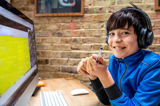 UK, Smiling boy in headphones having on-line lesson