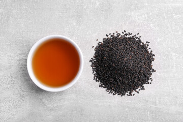 Black sesame seeds and oil on grey table, flat lay