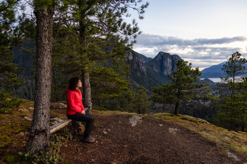 Naklejka na ściany i meble Adventurous Woman Hiking in the mountains during a Spring Sunset. Taken Squamish, North of Vancouver, British Columbia, Canada. Concept: Adventure, freedom, lifestyle