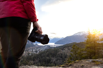 Adventure Travel Photographer Hiking in the mountains and taking pictures during a Spring Sunset. Squamish, North of Vancouver, British Columbia, Canada.