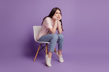 Fototapeta na wymiar Portrait of sad unhappy woman sit chair think isolated on violet background