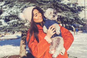 Beautiful Woman Hugging  Her Cute Havanese Dog in the Winter Forest. Pet and Owner Outdoor