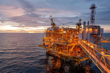 Offshore oil and gas central processing platform in sun set which produce raw gas, crude and hydrocarbon then sent to onshore refine, petrochemical industry. Power and energy business. - obrazy, fototapety, plakaty