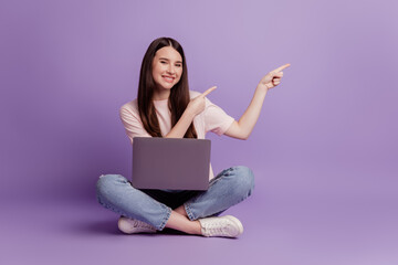Photo of girl with laptop direct fingers empty space on purple background