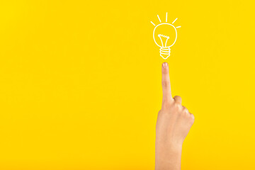 Children's hand with a raised index finger and a finished light bulb. Attention sign or idea. 