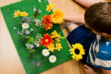 childhood meadow. kid playing with artificial flowers on artificial grass