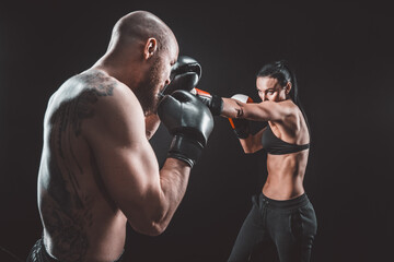 Fototapeta na wymiar Shirtless Woman exercising with trainer at boxing and self defen