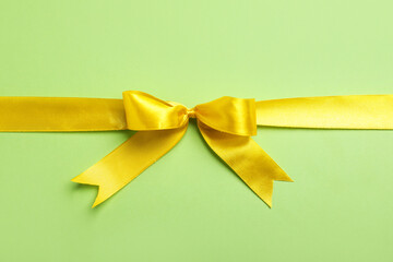 Yellow ribbon on green background, top view