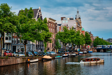 Fototapeta premium Amsterdam view - canal with boad, bridge and old houses