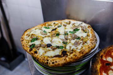 Pizza napoletana con salsiccia, funghi e mozzarella di bufala pronta per essere servita