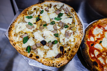 Pizza napoletana con salsiccia, funghi e mozzarella di bufala pronta per essere servita