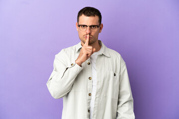 Brazilian man over isolated purple background showing a sign of silence gesture putting finger in mouth