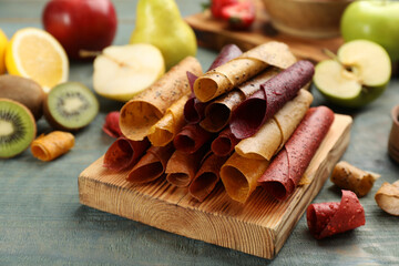 Fototapeta na wymiar Composition with delicious fruit leather rolls on blue wooden table