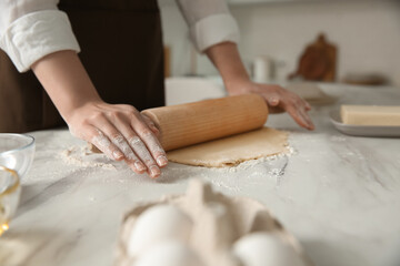 Woman rolling dough at table in kitchen, closeup - Powered by Adobe
