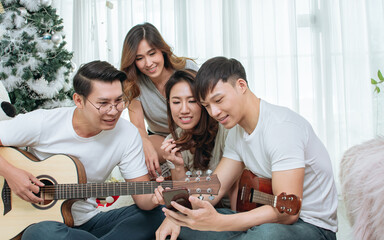 Group of Asian people or friends having party, singing and dancing together in living room at home. Lifestyle Concept.