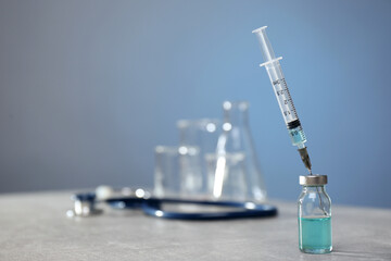 Syringe and vial on light grey table. Space for text