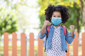 Child in face mask going at reopen school after covid-19 quarantine and lockdown. It is new normal for protection and prevention while outbreak of coronavirus or flu. Kids back to school concept.