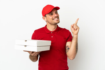 pizza delivery man with work uniform picking up pizza boxes over isolated  white wall pointing up a...