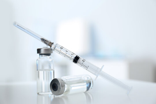 Syringe with vials of medicine on white table