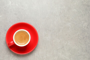 Aromatic coffee in red cup on light grey background, top view. Space for text