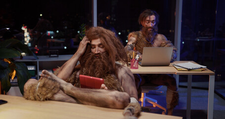 Couple of primeval savages working in modern office workspace doing project together using digital...