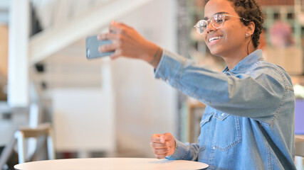 Cheerful African Woman taking Selfie on Smartphone at Cafe 