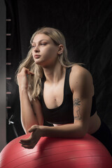 Fototapeta na wymiar Portrait of a young beautiful blonde athletic girl in a sports uniform in a fitness room.