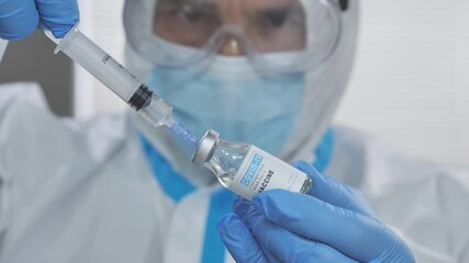 doctor wearing protective suit gloves and mask holding syringe,healthcare professional prepares covid-19 coronavirus vaccine bottle vial for injections - Powered by Adobe