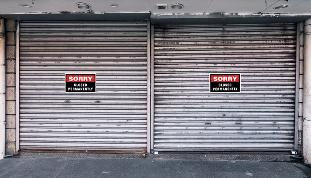 Two Closed Corrugated Metallic Roll Up Doors With Closed Permanently Signs. Concept Of Closed, Shuttered Or Bankrupt Establishment Or Business Background.