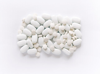 Fototapeta na wymiar White pills on a white background. Oblong and round pills close-up. Healthcare and medicine.