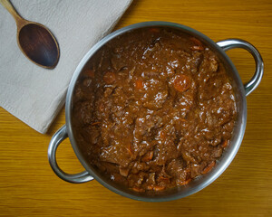 Fricando, Delicious and Traditional Catalan tapa, stew of beef in a metal pot decorated with a wooden spoon on a napkin. Top view