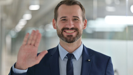 Portrait of Cheerful Middle Aged Businessman Waving at the Camera 