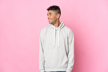 Young Brazilian man isolated on pink background looking side