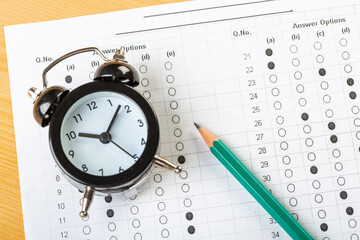 Fototapeta na wymiar alarm clock, optical form of standardized school test with bubble and black pencil, answer sheet, education concept