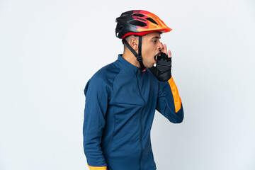 Young cyclist Brazilian man isolated on white background shouting with mouth wide open to the side