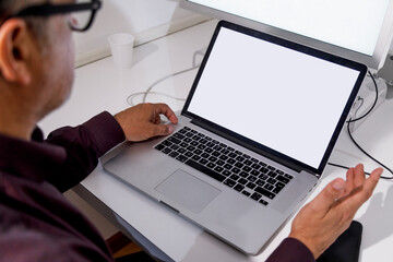 Dettaglio di un computer davanti al quale un uomo lavora  seduto alla scrivania di un ufficio